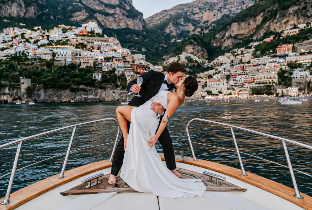 Bride and groom kissing on a yacht during an Amalfi Coast elopement in Italy with Positano lights in the background