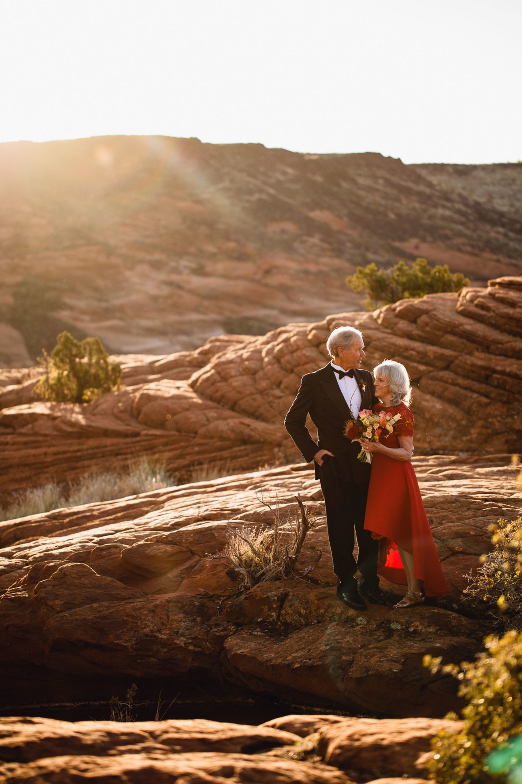 adventure elopement utah desert - recently married couple in the afternoon sun before breathtaking mountain view